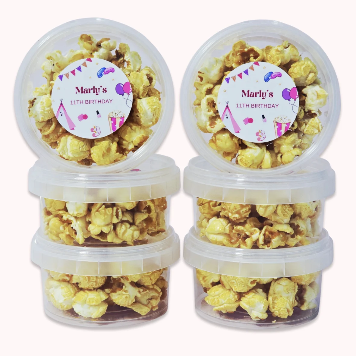 Personalised caramel popcorn party favours with pink sleepover theme birthday labels.