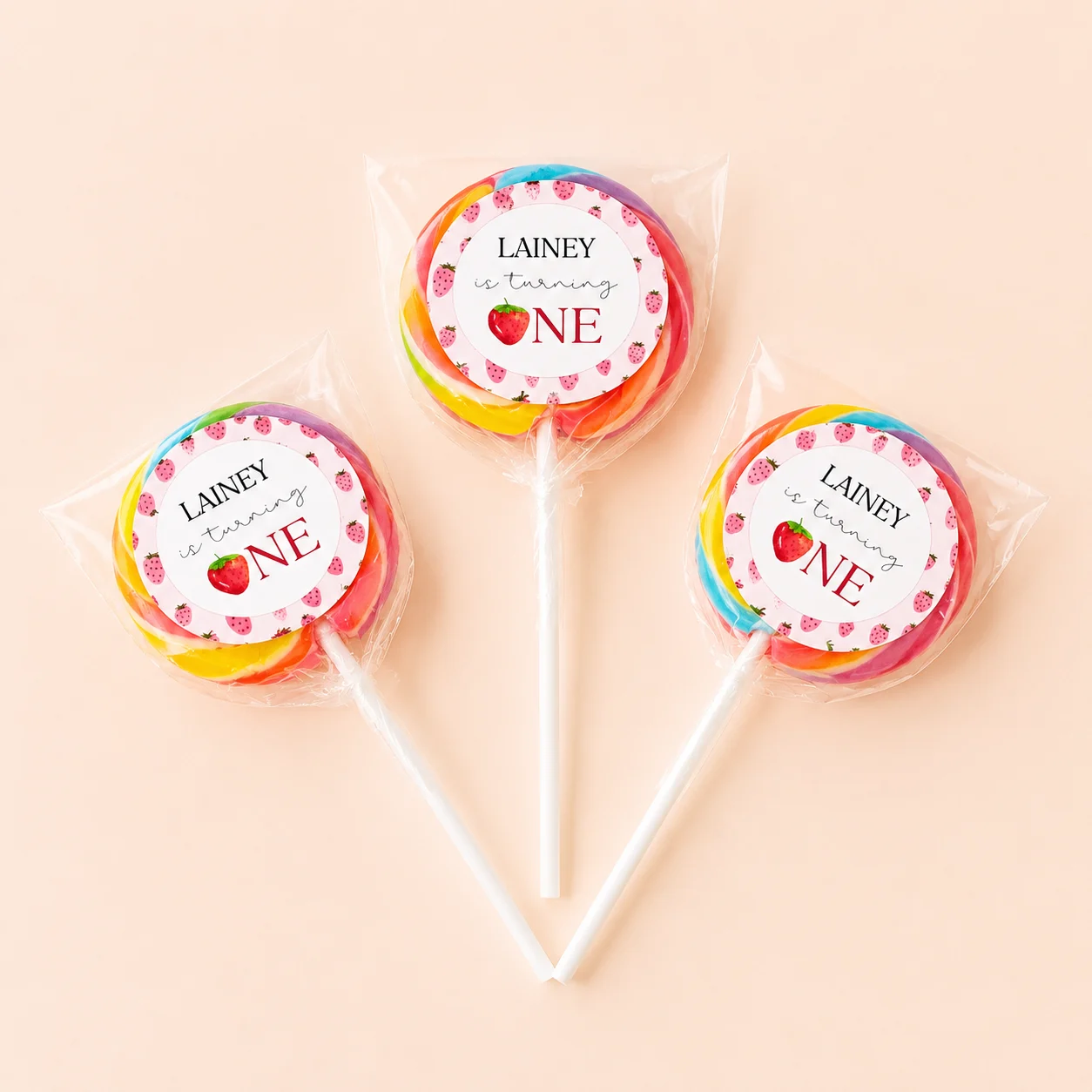 Strawberry personalised lollipops party favours with swirly lollipops and pink strawberry 1st birthday labels